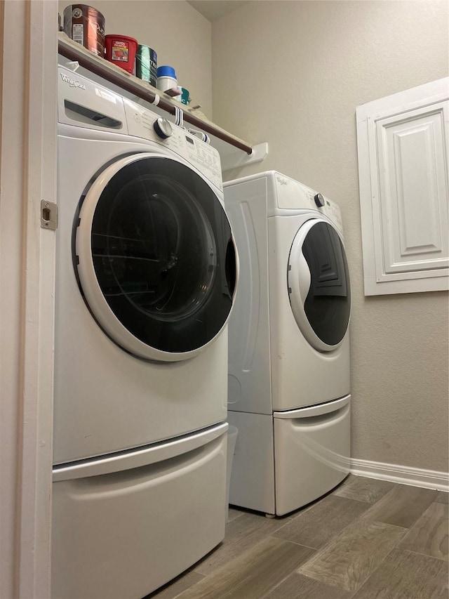 laundry area with baseboards, washing machine and dryer, wood finished floors, and laundry area