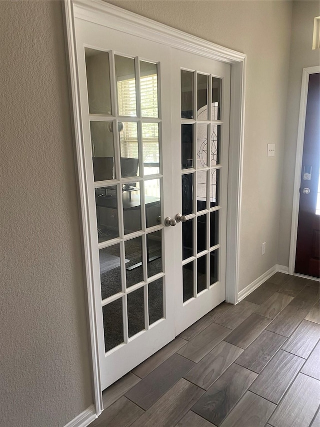 doorway featuring french doors, baseboards, a textured wall, and wood tiled floor