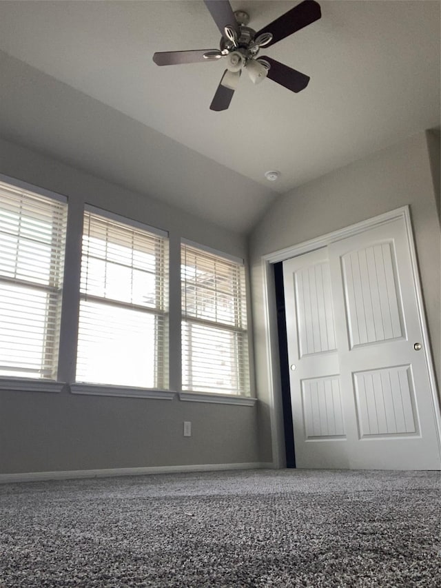 unfurnished bedroom with a closet, baseboards, lofted ceiling, and a ceiling fan