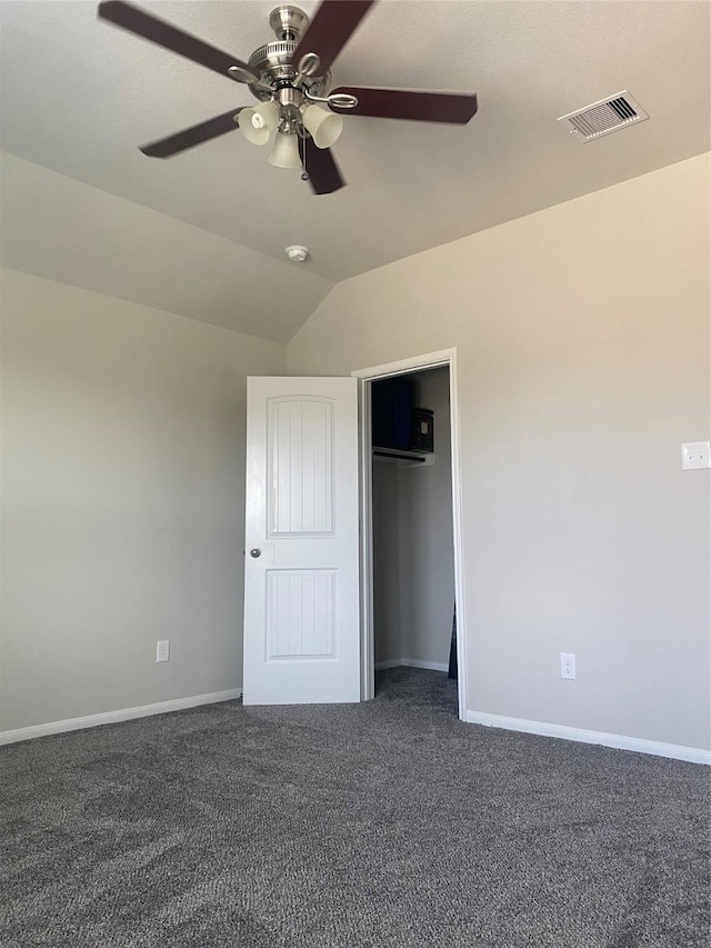 unfurnished bedroom with baseboards, visible vents, vaulted ceiling, a closet, and dark colored carpet