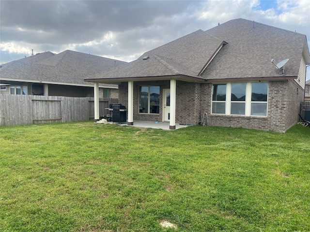 rear view of house with brick siding, a patio area, a lawn, and fence