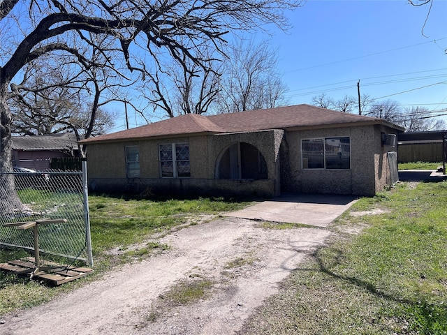 view of front of property featuring dirt driveway, a front yard, fence, and stucco siding