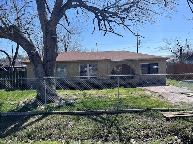 single story home with a front lawn, roof with shingles, fence private yard, and stucco siding