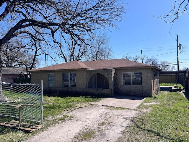 view of front of home featuring driveway, fence, a front lawn, and stucco siding