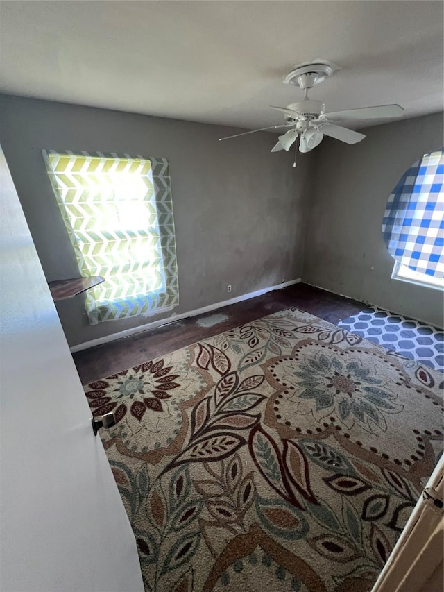 spare room featuring wood finished floors, a ceiling fan, and baseboards