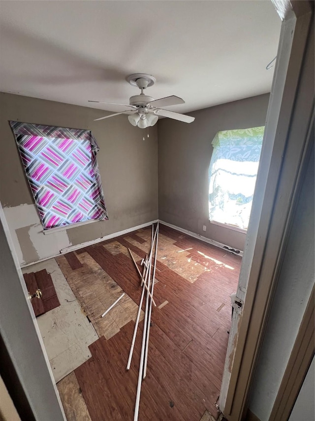 unfurnished room featuring ceiling fan, wood finished floors, and baseboards