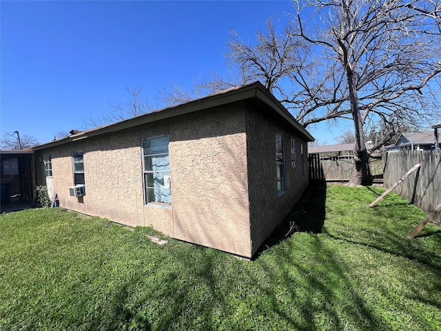 view of side of home featuring a yard, cooling unit, fence, and stucco siding