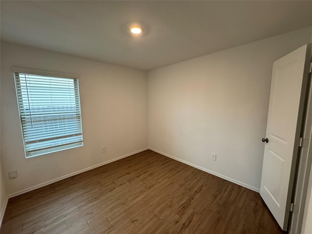 spare room with baseboards and wood finished floors