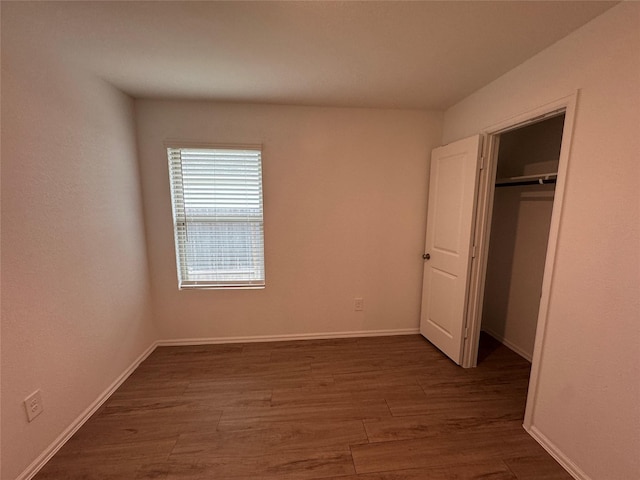 unfurnished bedroom featuring a closet, baseboards, and wood finished floors