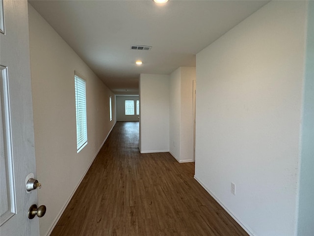 hall featuring dark wood finished floors, visible vents, and baseboards