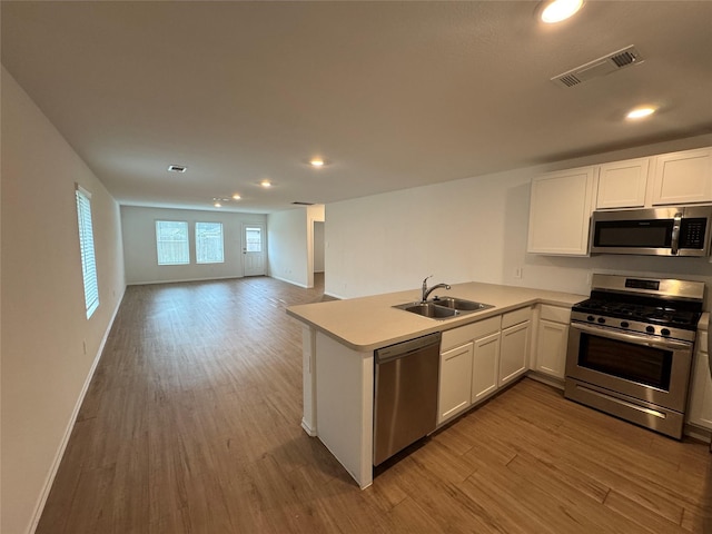 kitchen featuring stainless steel appliances, visible vents, a sink, and wood finished floors