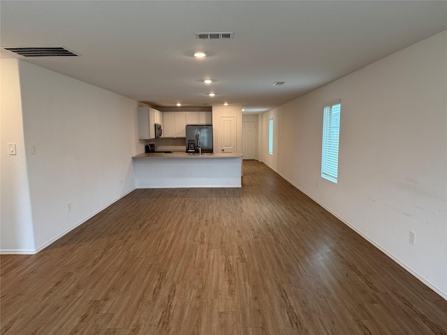 unfurnished living room featuring dark wood-style flooring, visible vents, and baseboards