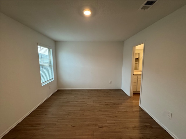 unfurnished room featuring baseboards, visible vents, and dark wood-type flooring