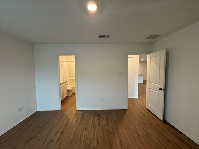 unfurnished bedroom featuring baseboards, connected bathroom, visible vents, and wood finished floors