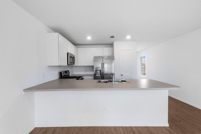 17594 Longwood Trace Ln, New Caney, TX 77357 - kitchen featuring appliances with stainless steel finishes, a sink, a peninsula, white cabinets, and wood finished floors