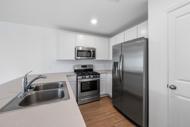17594 Longwood Trace Ln, New Caney, TX 77357 - kitchen featuring stainless steel appliances, a sink, white cabinetry, light wood finished floors, and light countertops