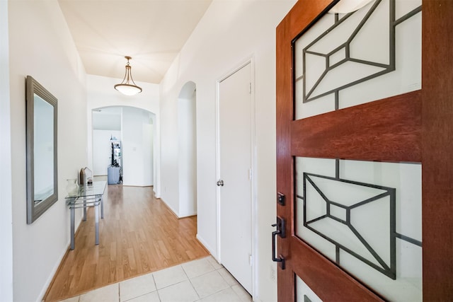 hallway with arched walkways and light tile patterned floors