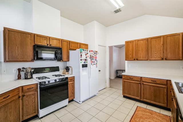 kitchen featuring black microwave, visible vents, light countertops, white fridge with ice dispenser, and gas stove