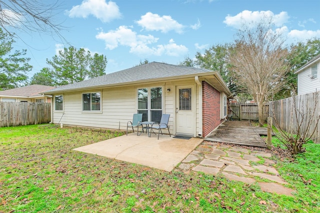 back of property featuring a patio, a fenced backyard, roof with shingles, a yard, and brick siding