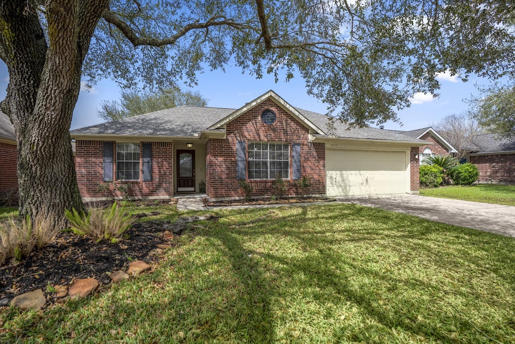 ranch-style house with brick siding, a shingled roof, concrete driveway, a front yard, and a garage