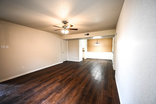 unfurnished room with baseboards, ceiling fan, visible vents, and dark wood-style flooring