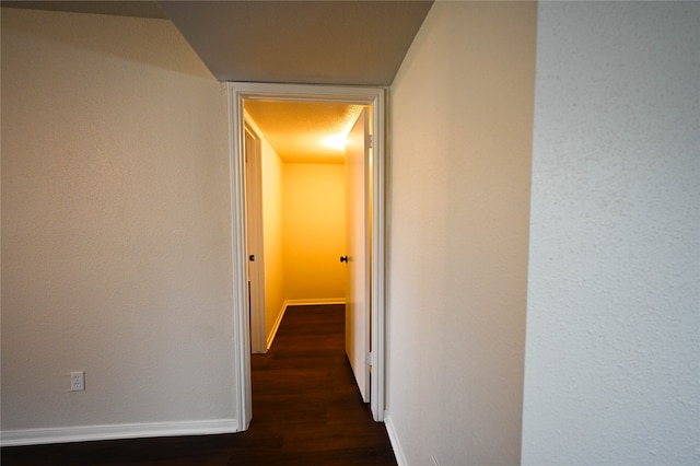 hall with dark wood-style flooring and baseboards