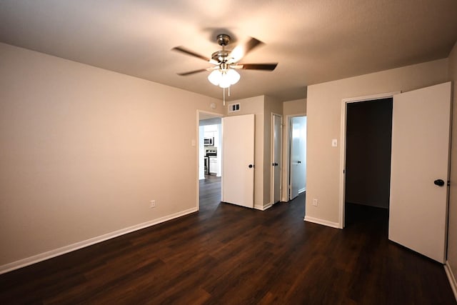 unfurnished bedroom featuring dark wood-type flooring, visible vents, ceiling fan, and baseboards