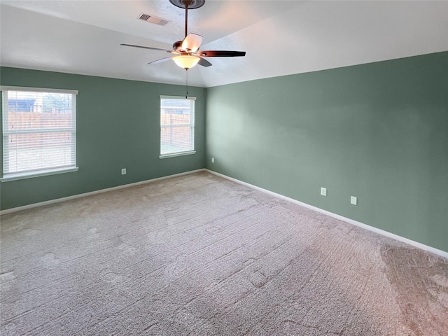 carpeted spare room with baseboards, visible vents, vaulted ceiling, and a ceiling fan