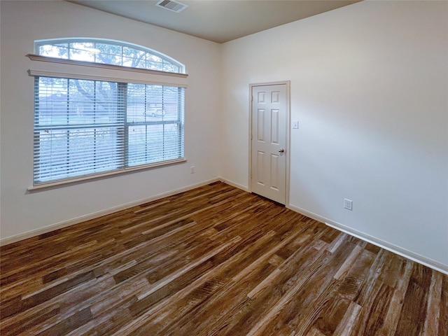 empty room featuring baseboards, visible vents, and dark wood-type flooring