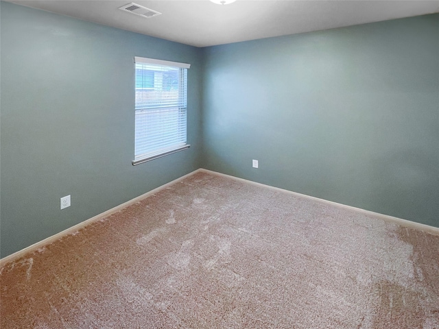 carpeted spare room with visible vents and baseboards