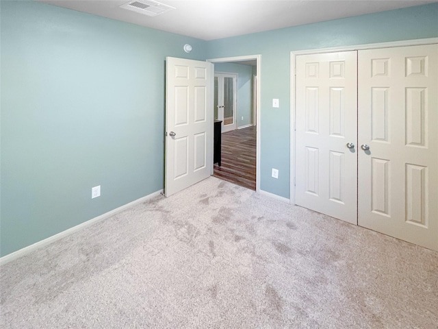 unfurnished bedroom with a closet, carpet, visible vents, and baseboards