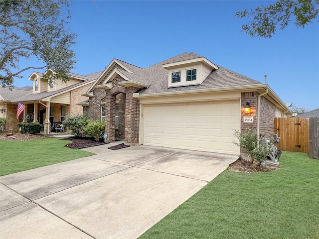 view of front facade with a shingled roof, a front yard, fence, and brick siding