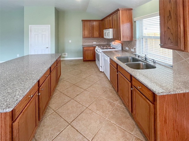 kitchen featuring white appliances, tasteful backsplash, brown cabinets, a sink, and light tile patterned flooring