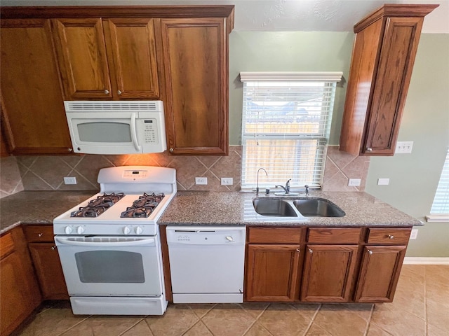 kitchen with white appliances, a healthy amount of sunlight, a sink, and brown cabinets