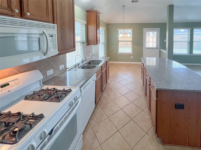 kitchen featuring white appliances, light tile patterned floors, decorative backsplash, brown cabinetry, and a sink