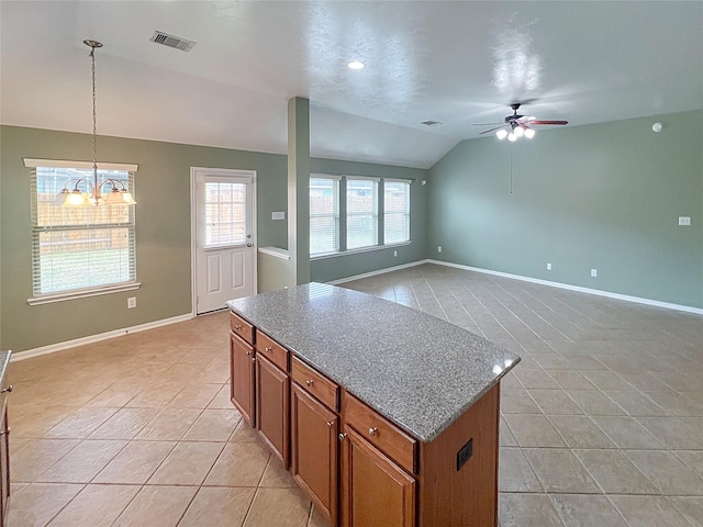 kitchen with a kitchen island, brown cabinets, vaulted ceiling, and light tile patterned floors