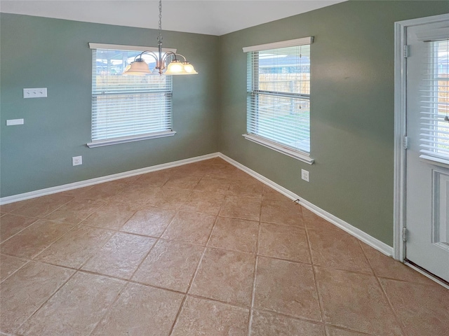 tiled spare room featuring a notable chandelier and baseboards