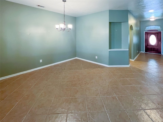 unfurnished room with baseboards, visible vents, and a chandelier