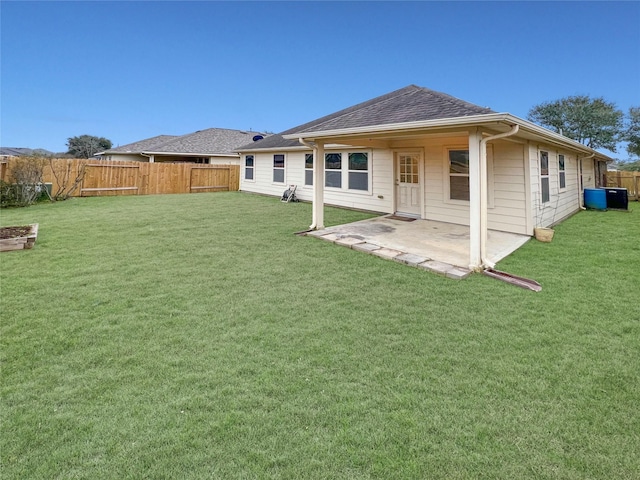 rear view of house with a yard, roof with shingles, fence, and a patio