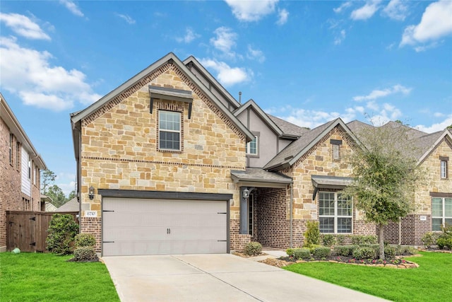 view of front of home featuring a front yard, fence, a garage, stone siding, and driveway