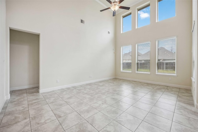 spare room with a towering ceiling, baseboards, visible vents, and a ceiling fan