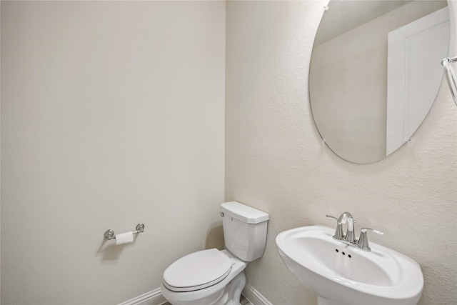 bathroom with baseboards, a sink, and toilet