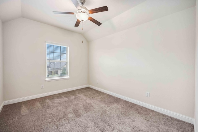 carpeted spare room featuring vaulted ceiling, a ceiling fan, and baseboards