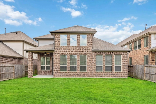 back of property with brick siding, a fenced backyard, and a yard