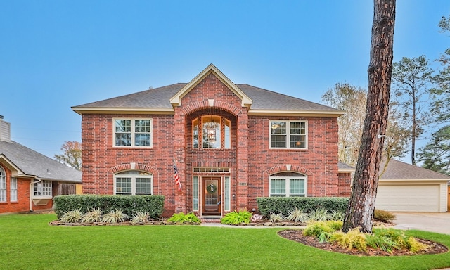 colonial inspired home featuring a front yard, brick siding, and roof with shingles