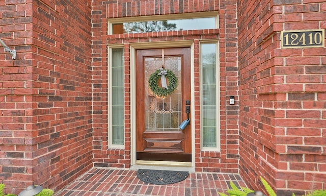 view of exterior entry featuring brick siding