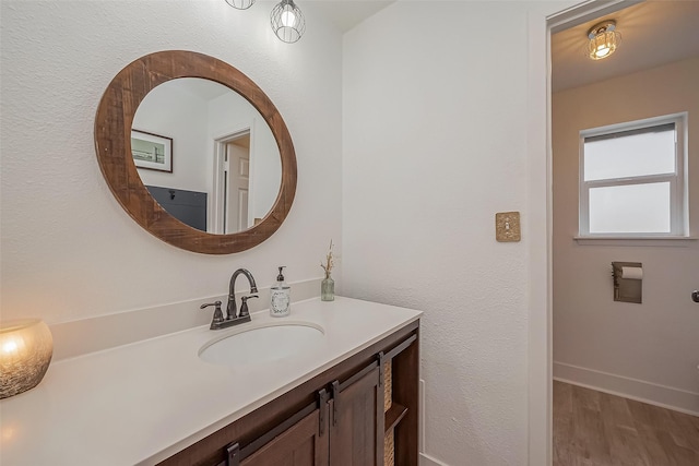 bathroom featuring baseboards, wood finished floors, and vanity