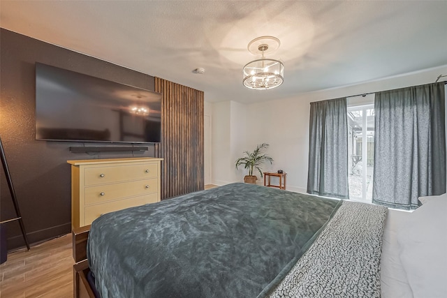 bedroom with a chandelier, light wood-style flooring, and baseboards