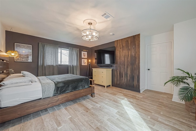 bedroom with visible vents, a notable chandelier, and light wood finished floors