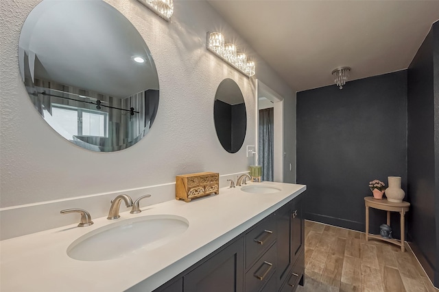 bathroom with double vanity, wood tiled floor, walk in shower, and a sink